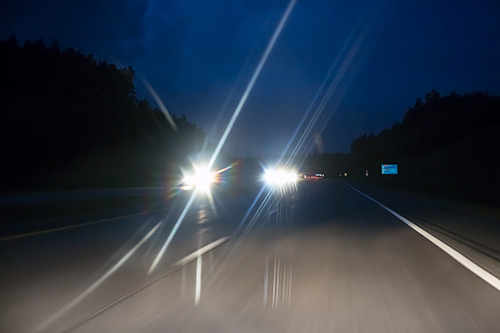 Night Car With Bright Headlights Approaching In The Dark