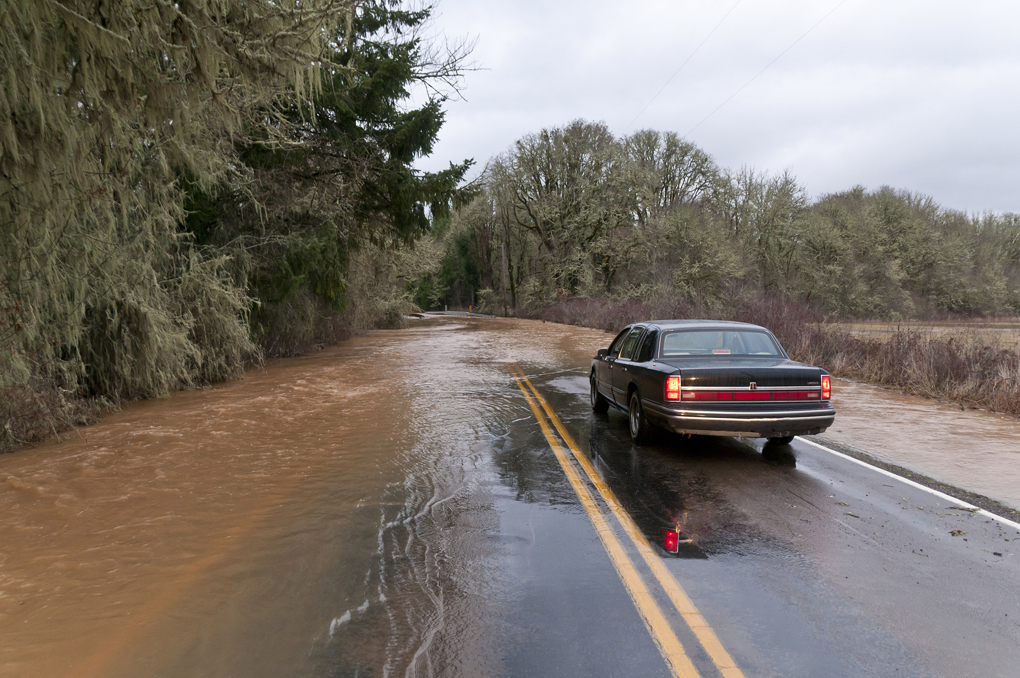 picture of a car driving through on flooded road